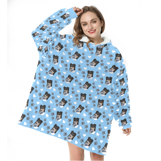 Woman wearing oversized blue hoodie with dog and paw print pattern.